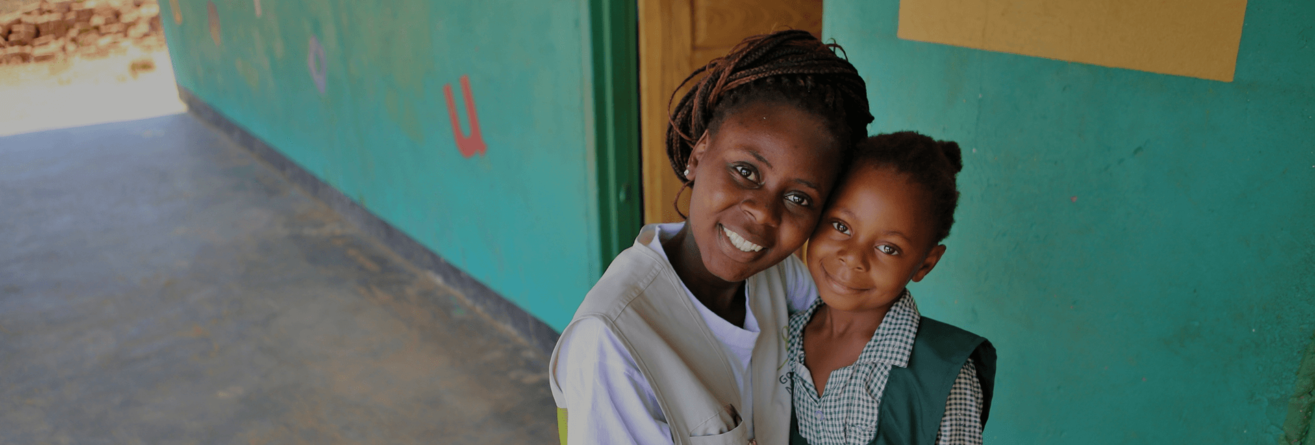 글로벌 아동권리 전문 NGO 굿네이버스 후원, 기부금 세액공제 안내 메인 이미지 / 굿네이버스 사업 현장에서 현지 직원과 해외 아동이 카메라를 바라보며 환하게 웃는 모습 이미지