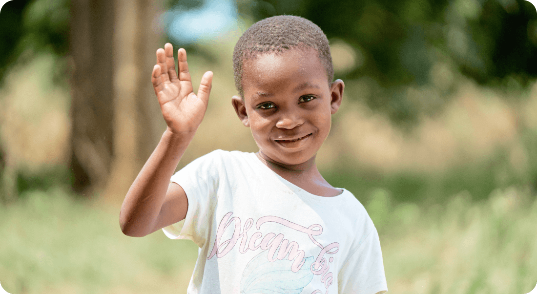 굿네이버스 해외아동 1:1 결연 후원으로 건강하게 성장하여 활짝 웃으며 손을 흔드는 아이