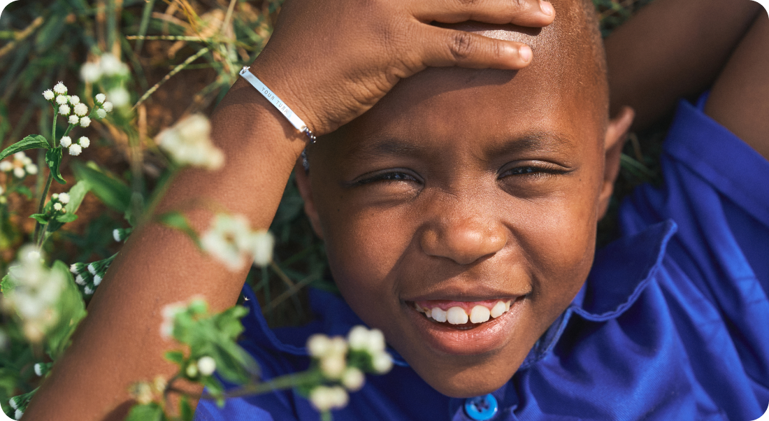 굿네이버스 기부 굿즈 캠페인 유어턴 팔찌를 착용하고 환하게 미소짓는 남자 아동의 모습