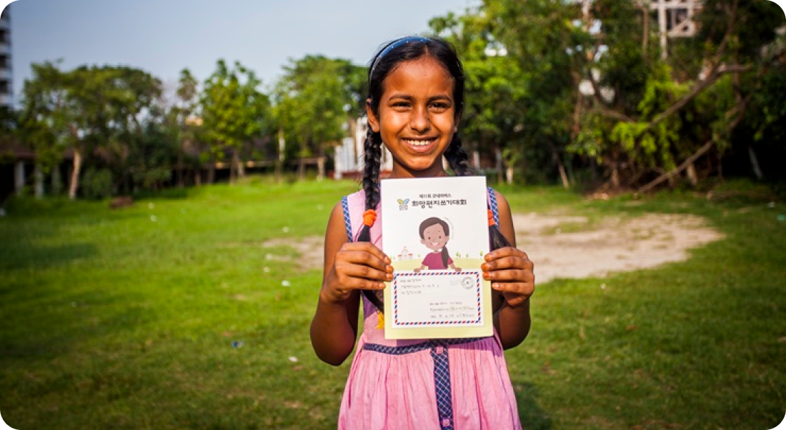 한국 친구들의 응원 메시지가 담긴 희망편지를 전달받고 미소 짓는 굿네이버스 사업국 아동의 모습