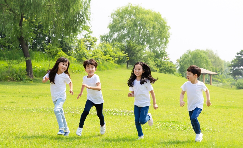 아이들 네명이 잔디밭에서 뛰어가는 이미지