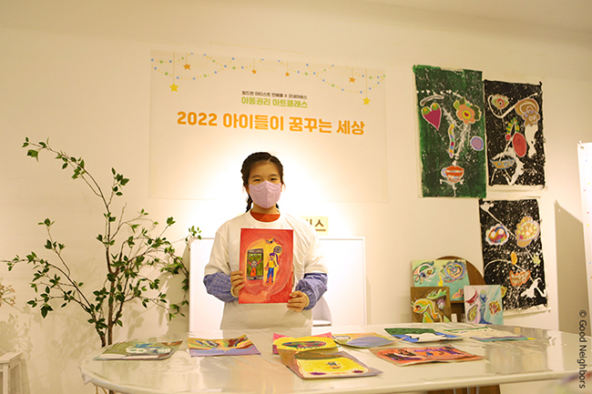 아트클래스에서 그린 그림을 들고 있는 어린이 모습
