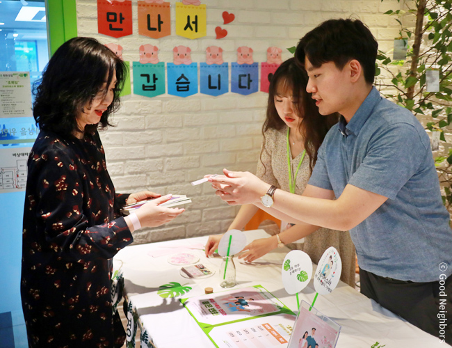 굿네이버스 직원이 굿멤버스이에 방문한 회원님을 맞이하고 있는 이미지