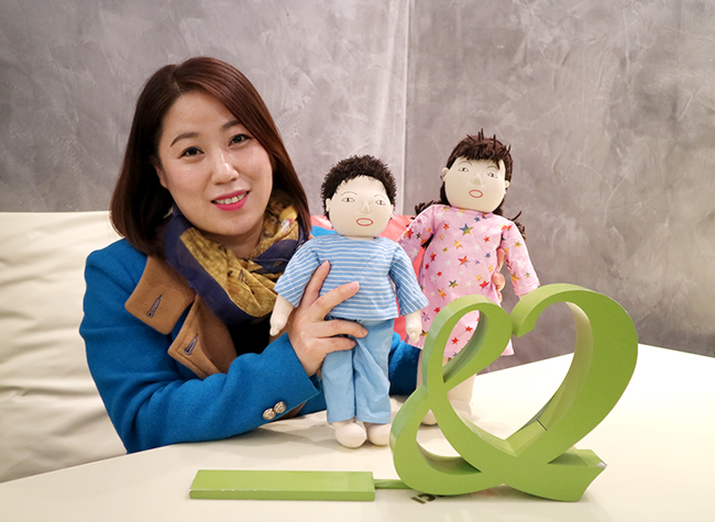 굿네이버스 모형 앞에서 교육용 인형을 들고 환하게 웃고 있는 이혜주 회원님 이미지