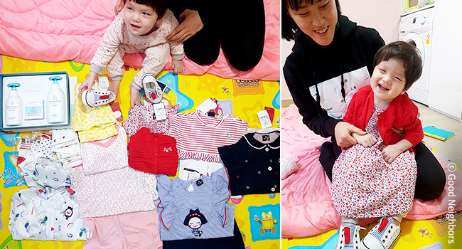 후원자님들이 보내주신 예쁜 옷, 유아용품 선물을 받고 환하게 웃고 있는 은희와 엄마 이미지