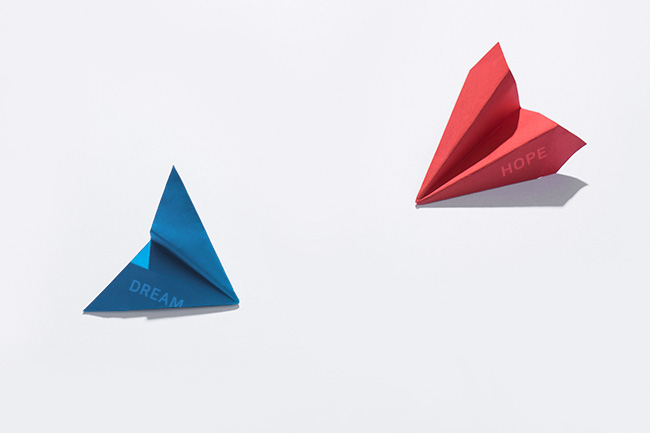 DREAM이 적혀 있는 파란색 종이 비행기와 HOPE가 적혀 있는 빨간색 종이 비행기가 놓여져 있는 이미지