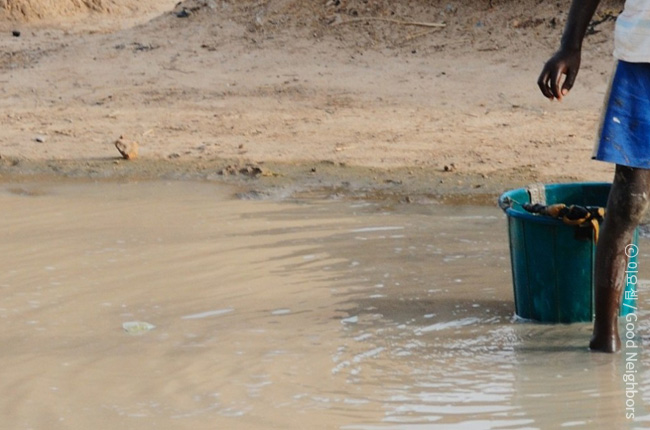 깨끗하지 않은 물에 발을 담그고 있는 아이의 모습