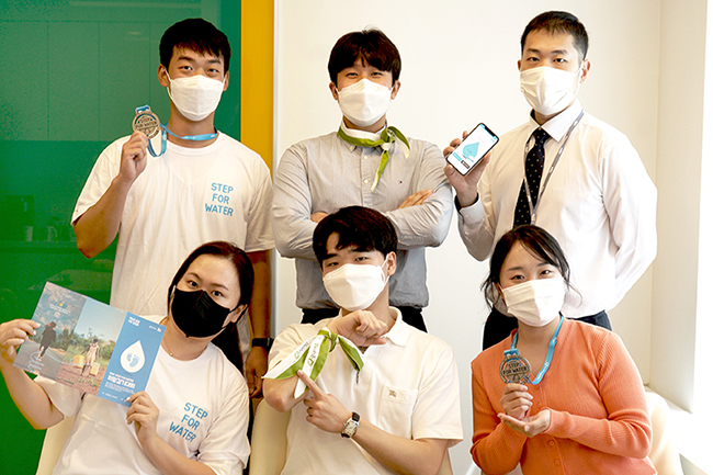 희망걷기대회 굿워터 키트 내 물품 (메달, 브로셔, 전용 앱)을 들고 포즈를 취하는 윌로펌프 임직원들의 모습