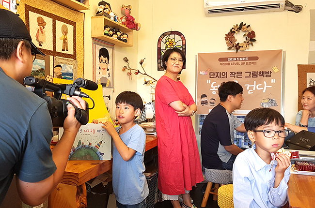 초록색 츄리닝을 입고 하얀색 머리띠를 두른 성인 남성이 머리를 만지며 고민하는 이미지