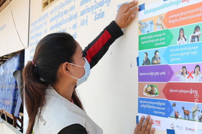 코로나19 예방 포스터를 부착하고 있는 모습(캄보디아)